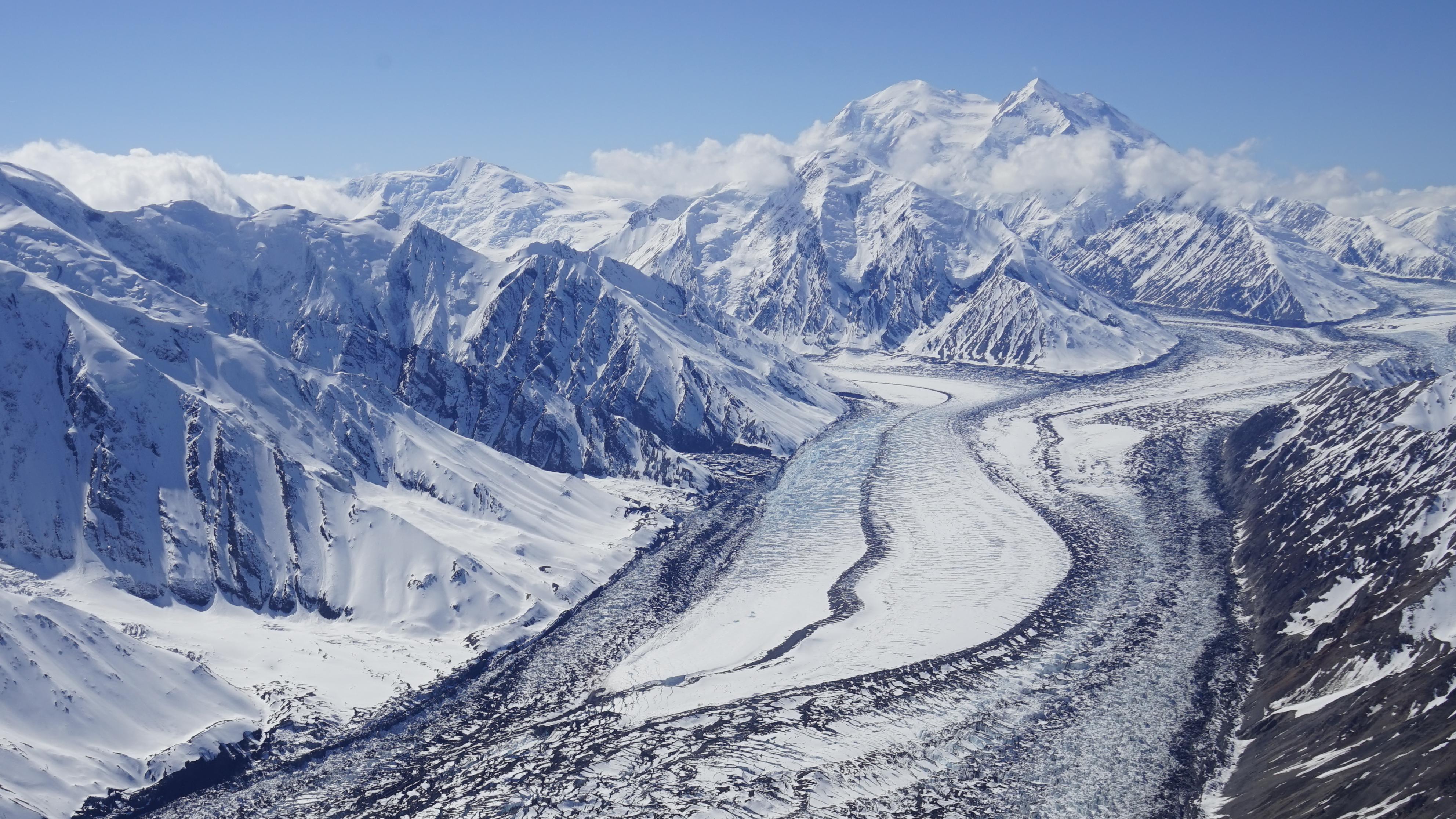 a huge snowy mountain with vast glacier flowing off it