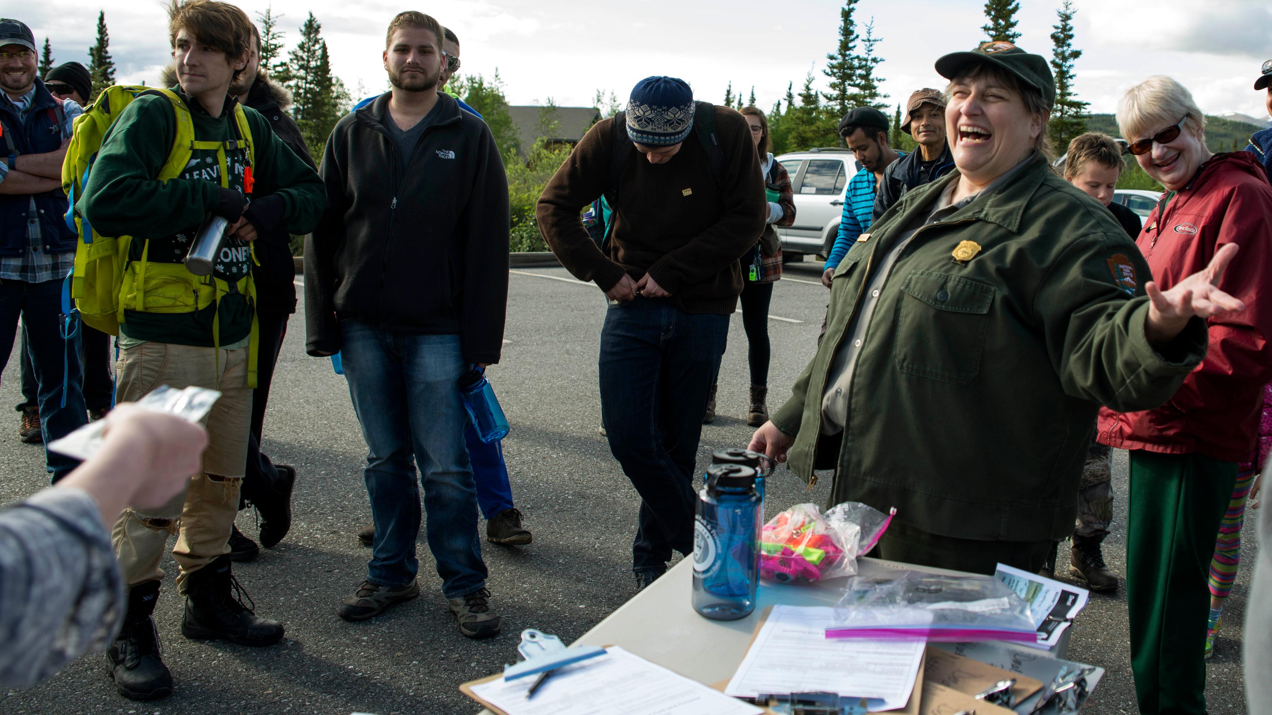 crowd of people around a park ranger, next to a table full of clipboards