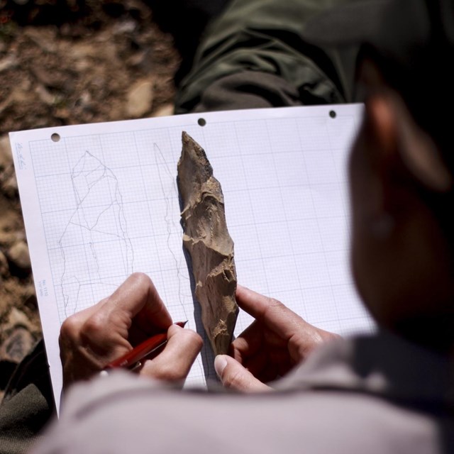 a person draws an archeological artifact