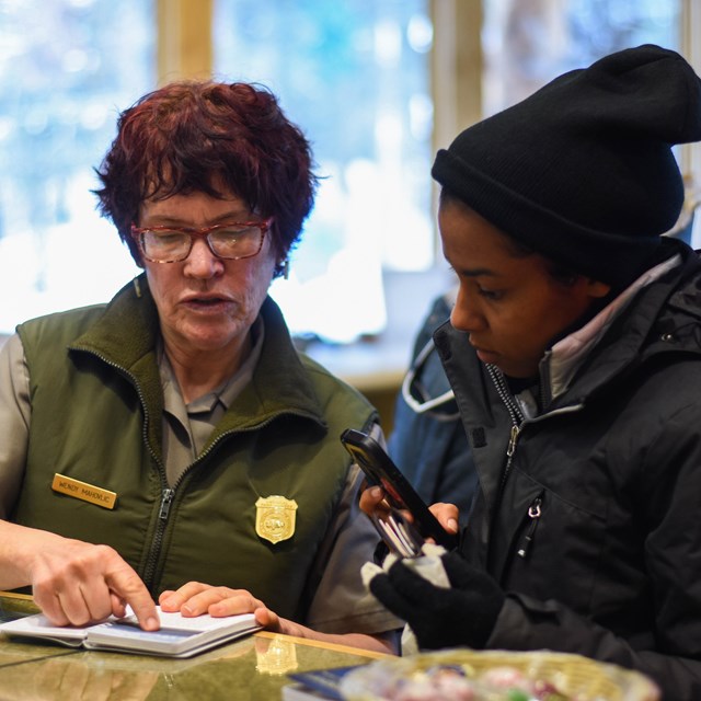 a park ranger speaks to a young woman at a desk
