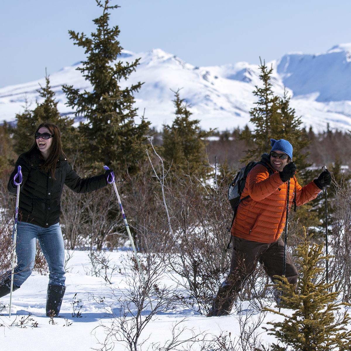 a man and woman hike using snowshoes