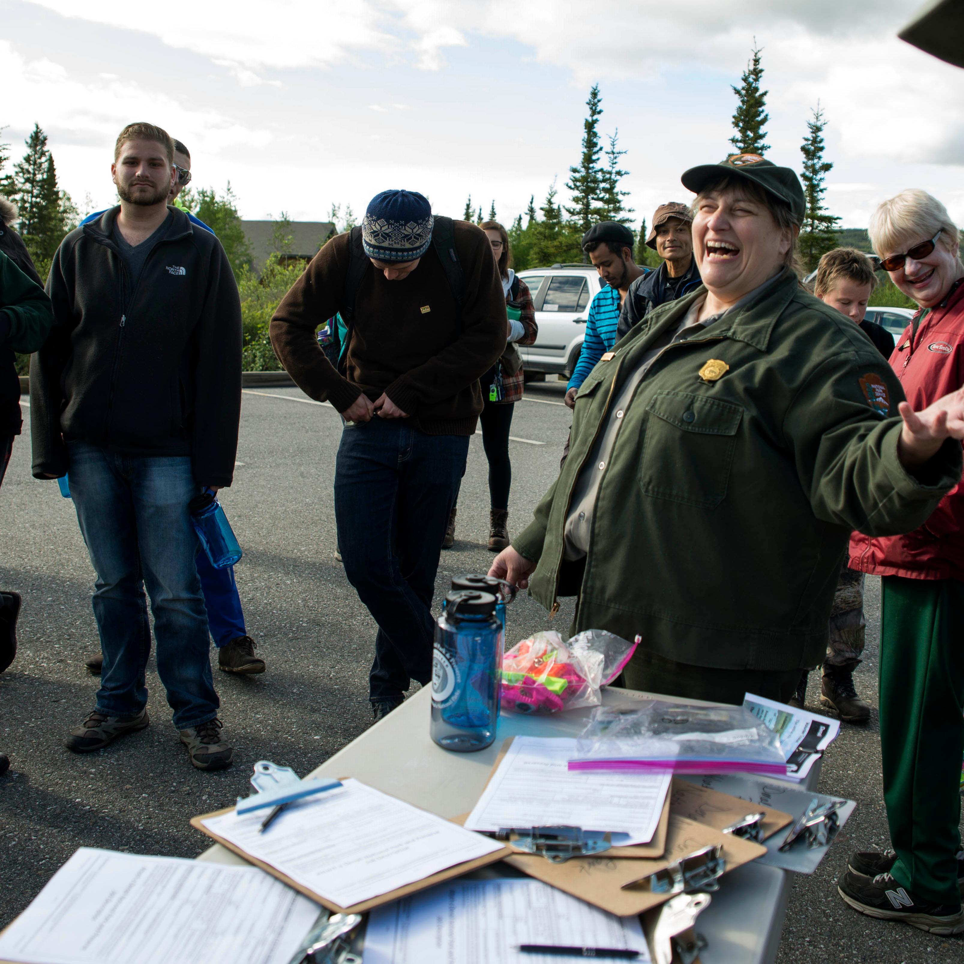 crowd of people around a park ranger, next to a table full of clipboards