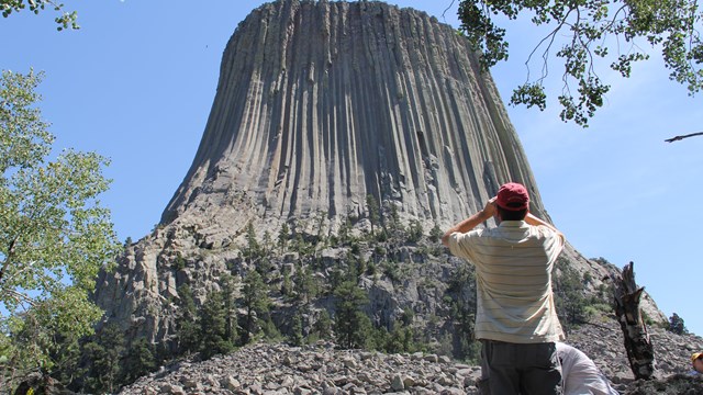 man with binoculars in foreground, Devils Tower in background