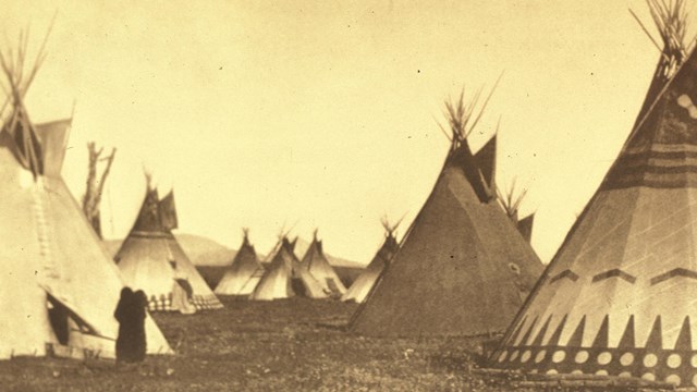 Several teepees in an old sepia image.