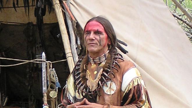 An American Indian speaking outside a replica tipi