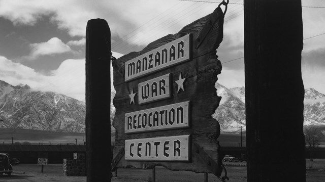 Black and white image of wooden sign reading Manzanar War Relocation Center.