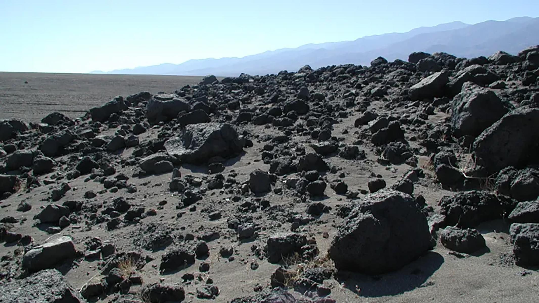 The photograph showcases a barren landscape covered in dark, jagged rocks.