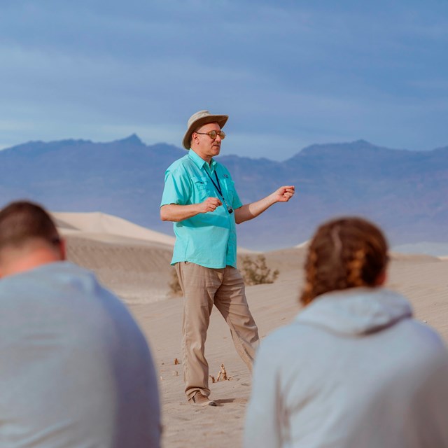 In the center of the image, a man wearing a light blue shirt, khaki pants.