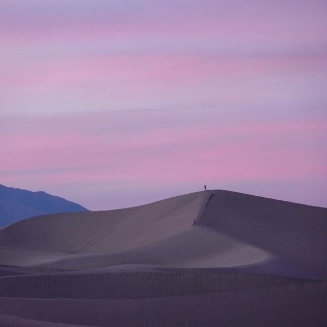 The sand dune in the foreground features smooth, sweeping curves that appear almost silky.