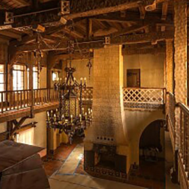 Warm interior shot of a historic building known as Scotty's Castle, featuring large wooden beams.