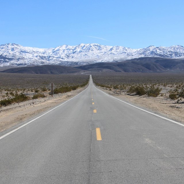 View is of a winding Highway 190 looking towards the snow covered Panamint Mountains. NPS