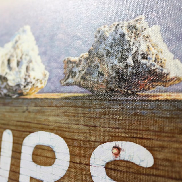 Close-up image of oil painting showing rocks on top of a wooden sign reading 
