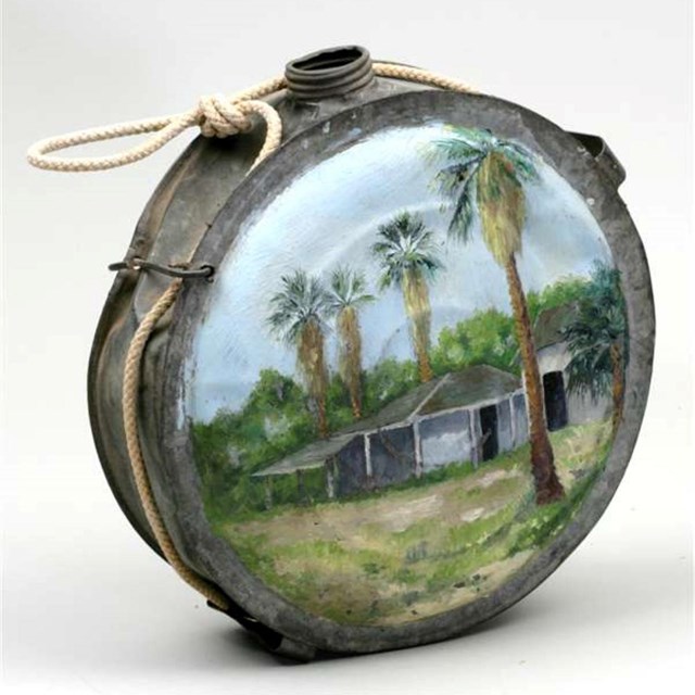 Metal canteen with painted image of palm trees and two buildings. NPS