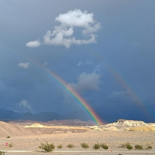 Against a backdrop of stormy, deep blue clouds, two rainbows.