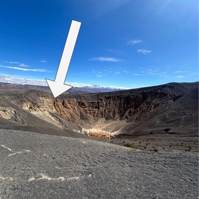 Deep crater covered around the rim with dark black debris.
