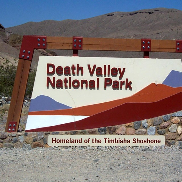 A large, stylized sign marks the entrance to Death Valley National Park. 