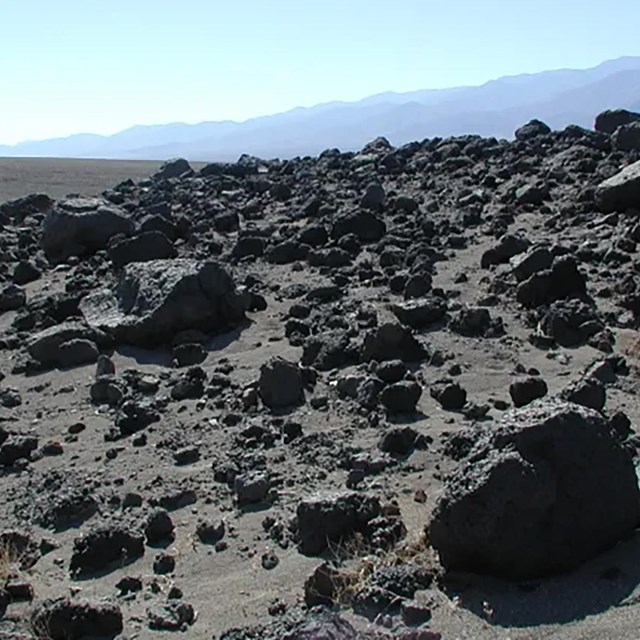 The photograph showcases a barren landscape covered in dark, jagged rocks.