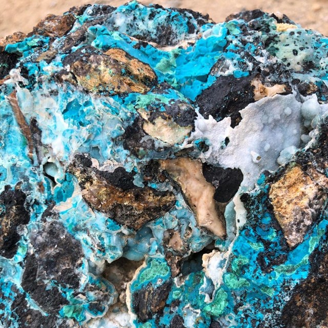 A closeup of a rock containing striking veins of blue, turquoise, and white coloration. 