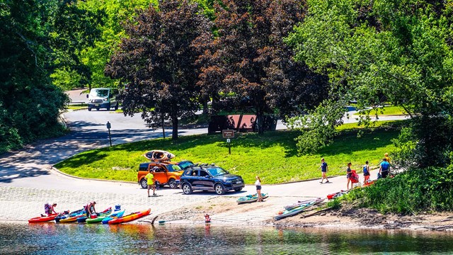 A boat launch with canoes and kayaks near the water.