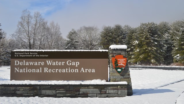 An entrance sign to the park covered in a blanket of snow.