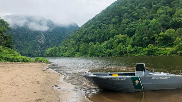 A ranger boat on a sandy boat launch with the Delaware Water Gap in the background.