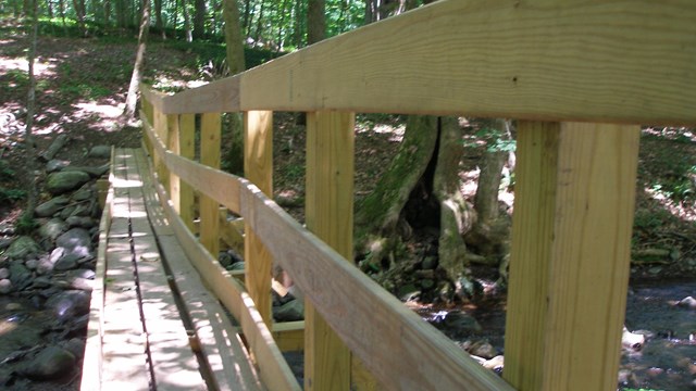 A thin wooden bridge crossing a creek.