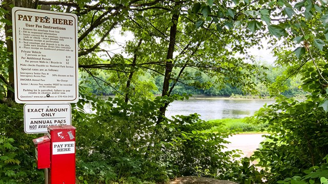 An Iron Ranger fee box sits on the left while off to the right is the Delaware river