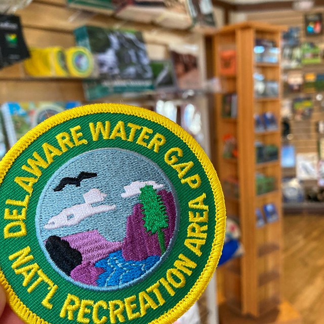 A circular patch for the Delaware Water Gap NRA with other bookstore items behind it.