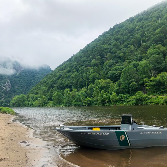 A partol boat on a sandy boat launch. The Delaware Water Gap is in the background.