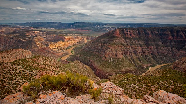 A river slicing through layered rock formations.