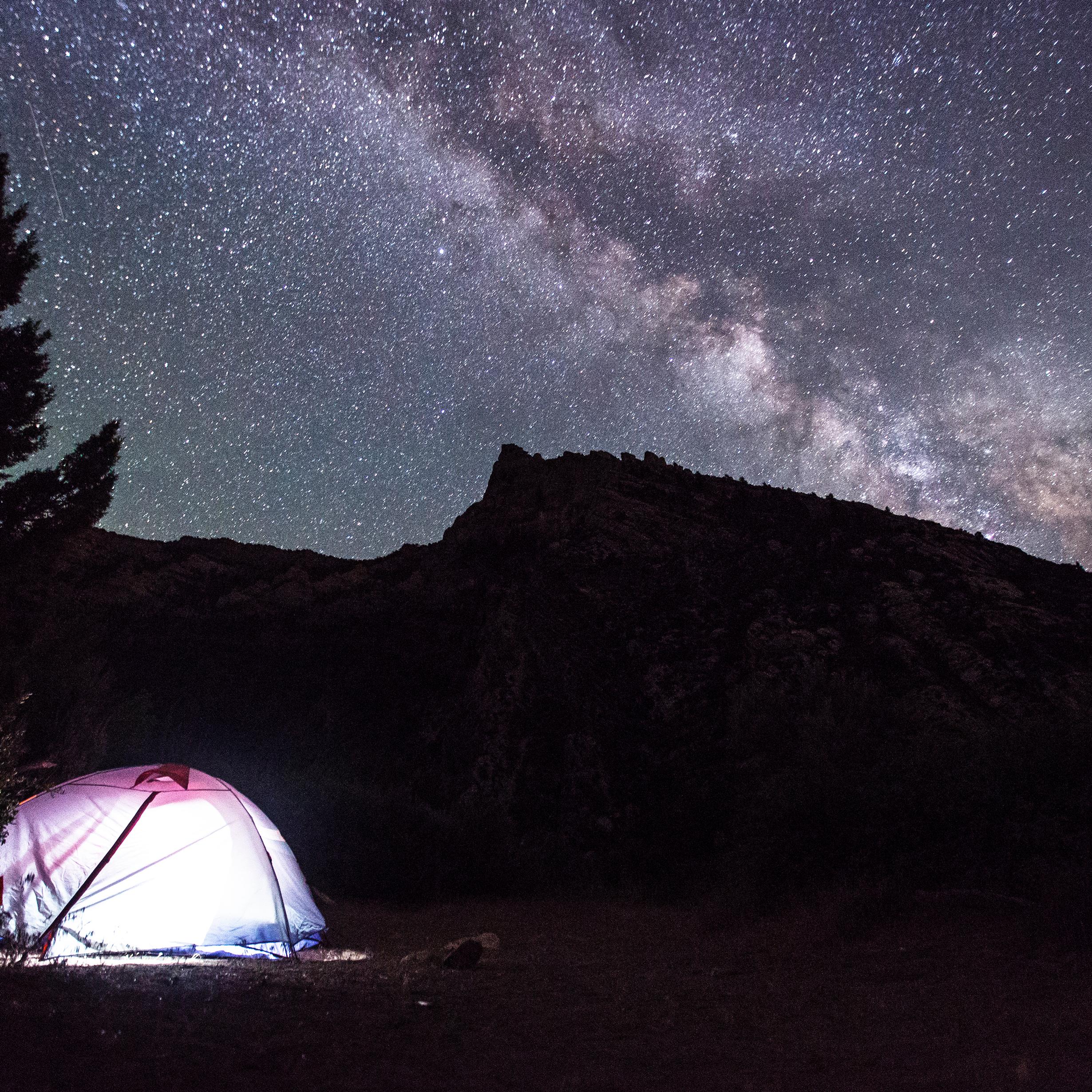 lighted tent underneath a starr filled night sky