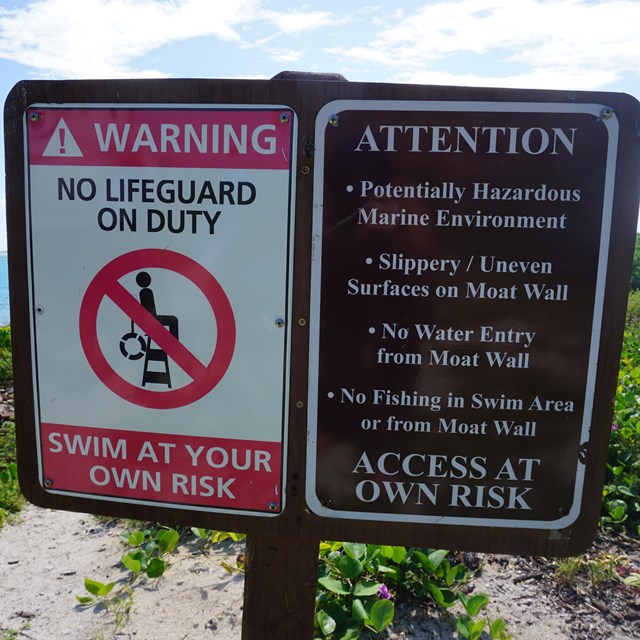 Two signs warning visitors of potential aquatic threats