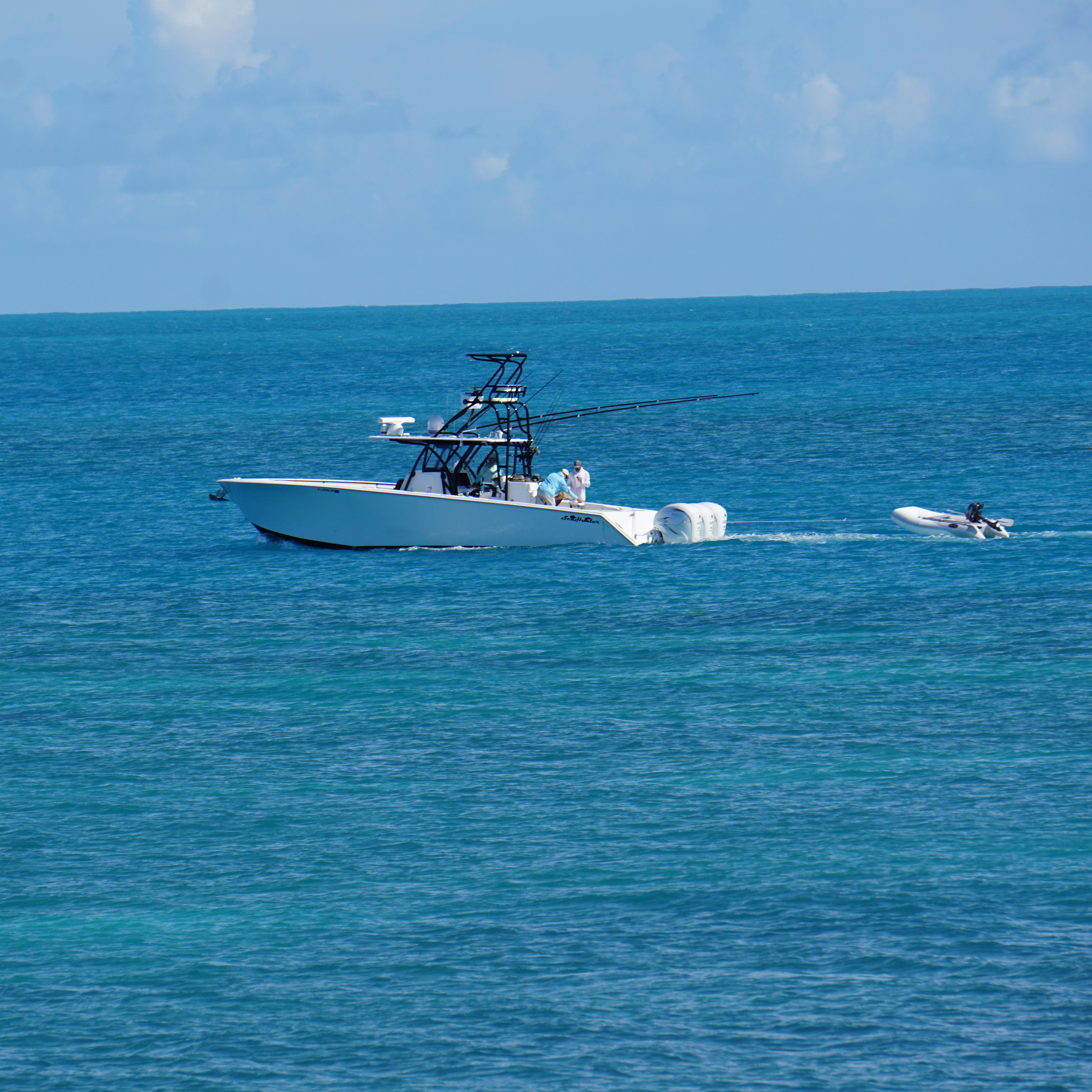 A white boat floating on blue ocean waters with a blue sky in the background