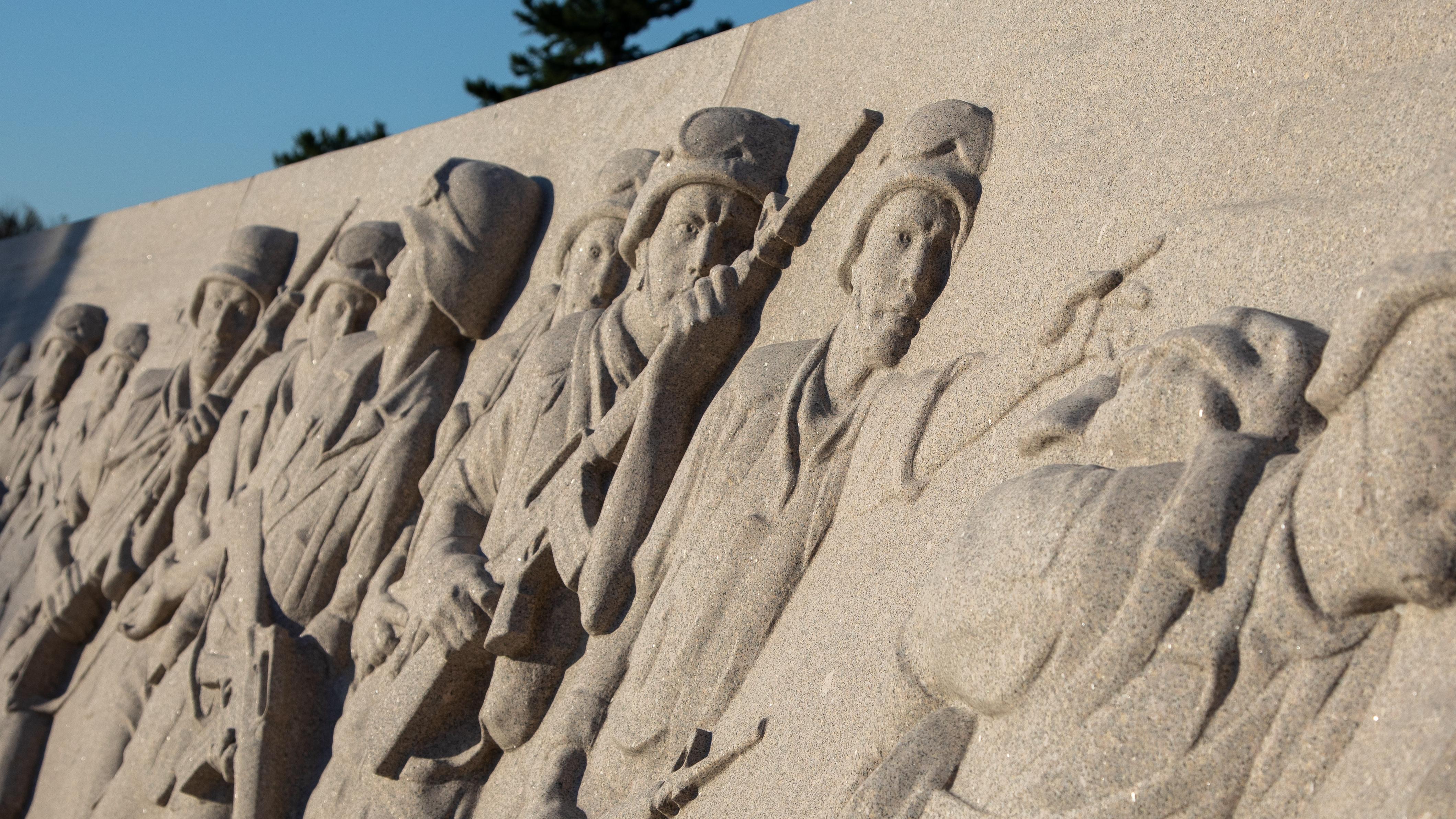 A detail photo of soldiers on in relief on a stone wall.