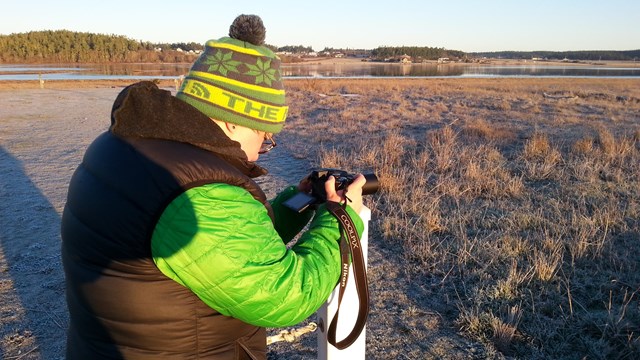 Woman takes photos in the chilly winter dawn.