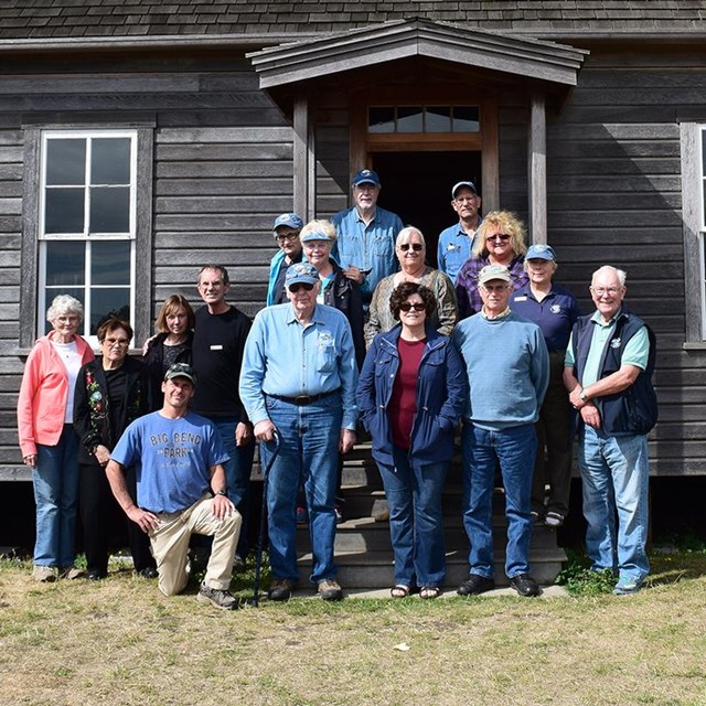 group of volunteers stand on the front porch of the historic Jacob Ebey House.