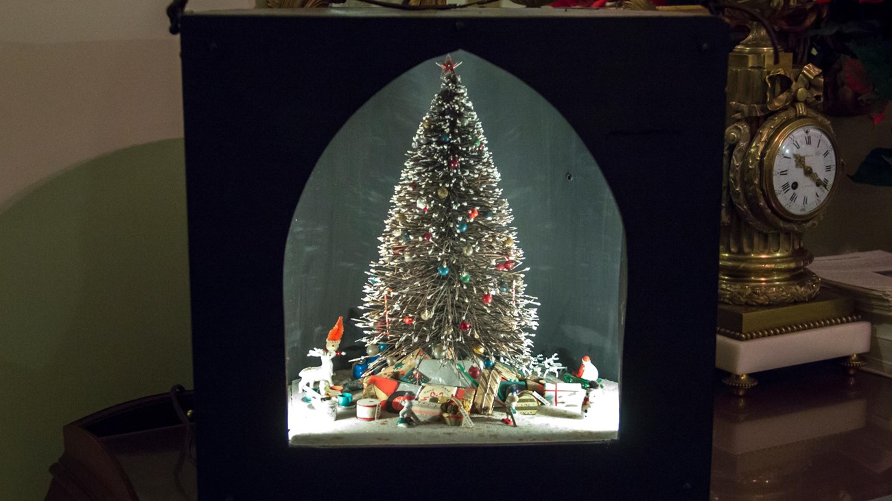 A black shadow box with a Christmas tree inside
