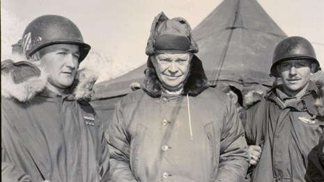 A black and white image showing General Eisenhower walking in winter clothing in Korea