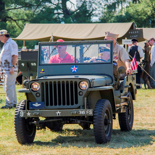 A World War II era Jeep is driven through the World War II weekend living history camp.
