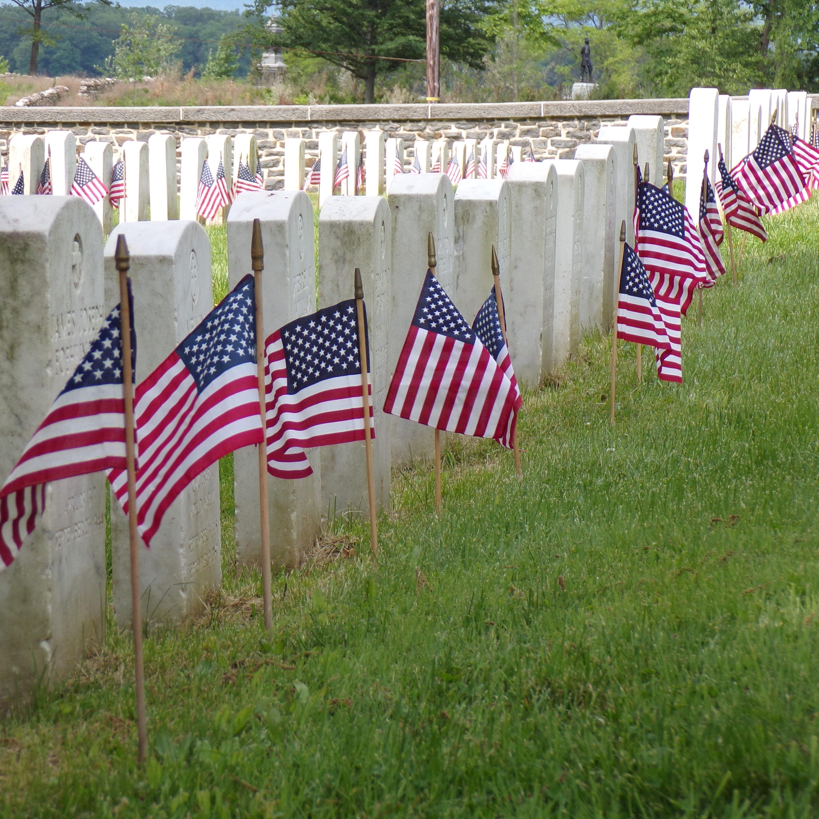 A color image showing American flags in front of white headstones