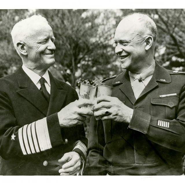 A black and white image of two men holding glasses and smiling