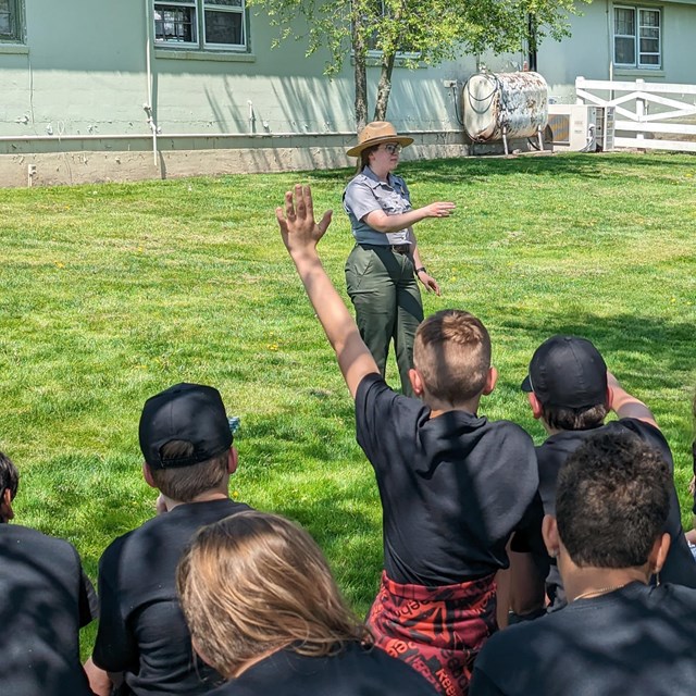A color image of a park ranger speaking to a group of students wearing matching shirts