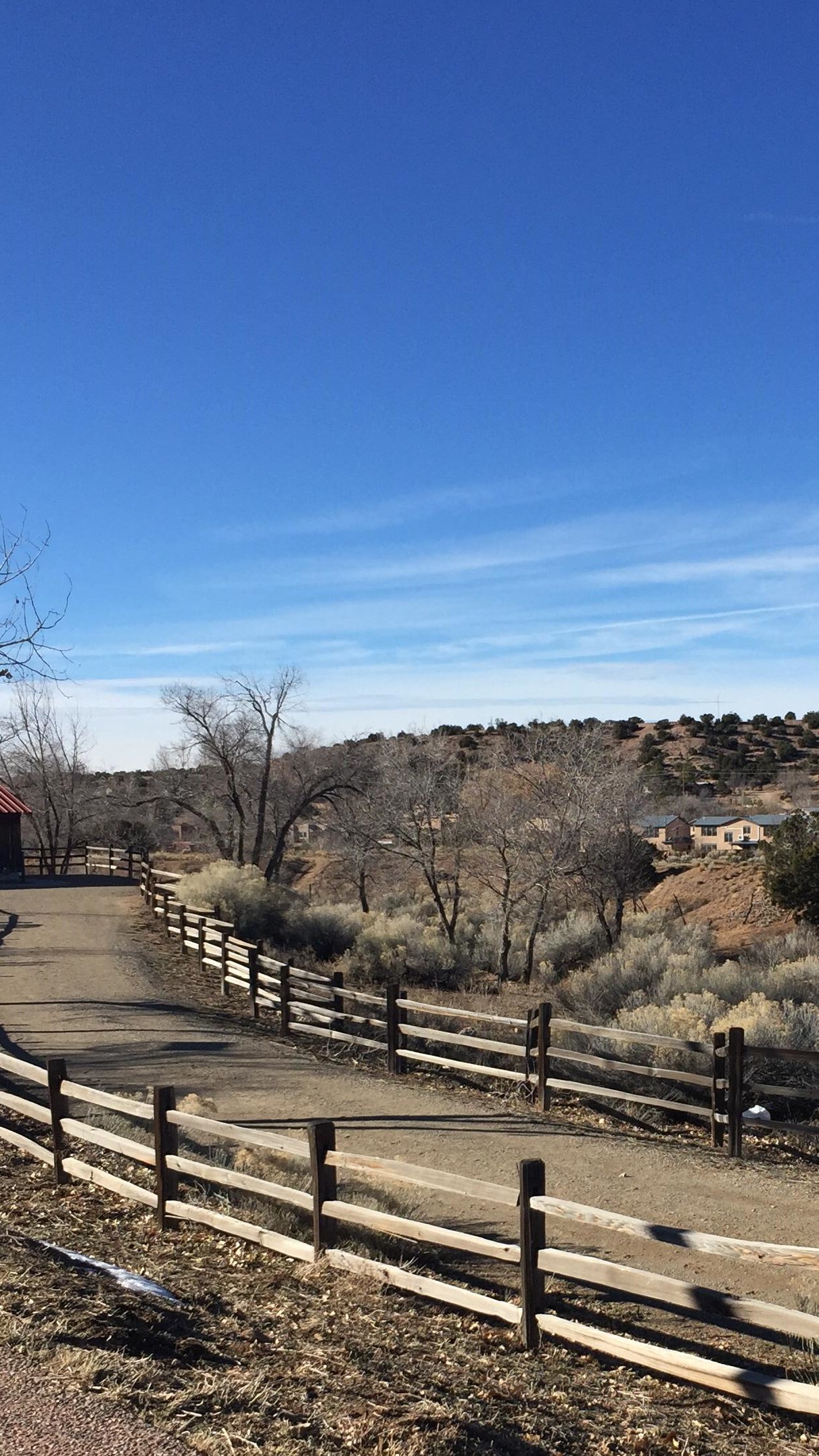 A pedestrian path, lined with a wooden fence, leads into a desert.