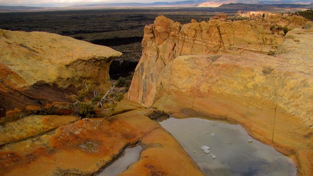 Pools of water on top of a high sandstone bluff.