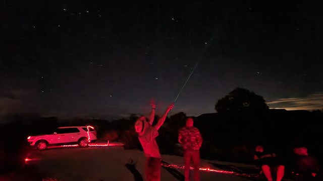 A ranger points to the sky during an astronomy program. 