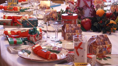 A dining table set for Christmas dinner with many decorations.