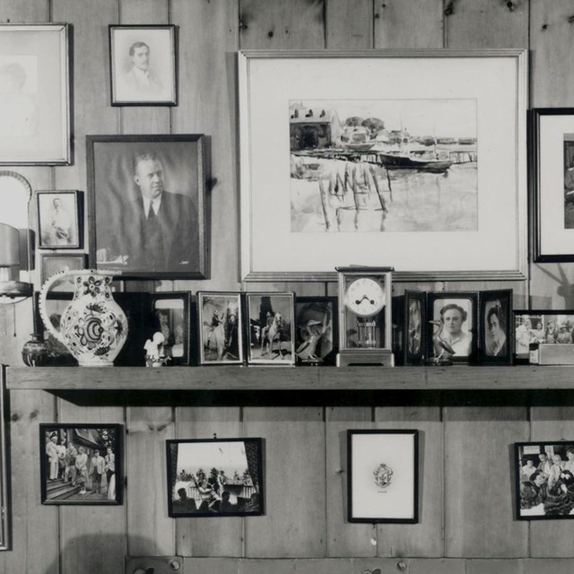 A room with many framed photographs on the walls and furniture.
