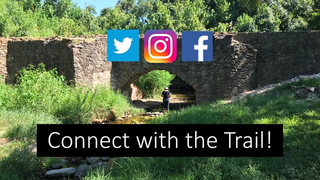 A person stands under a stone bridge with a green grass in the foreground. "Connect with the Trail"