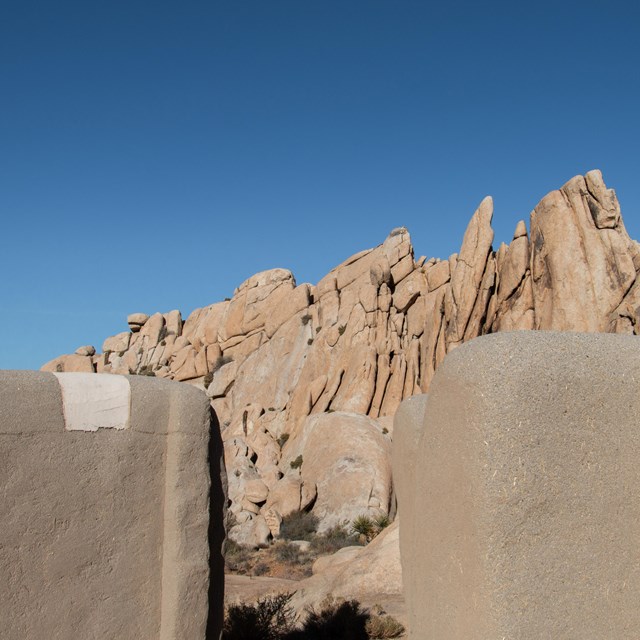 Formaciones rocosas vistas a través de una estructura de adobe en primer plano.
