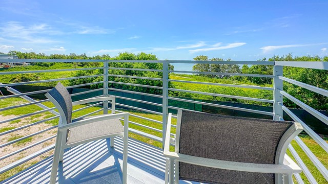 Two chairs on a balcony overlooking trees, vegetation and Florida Bay.